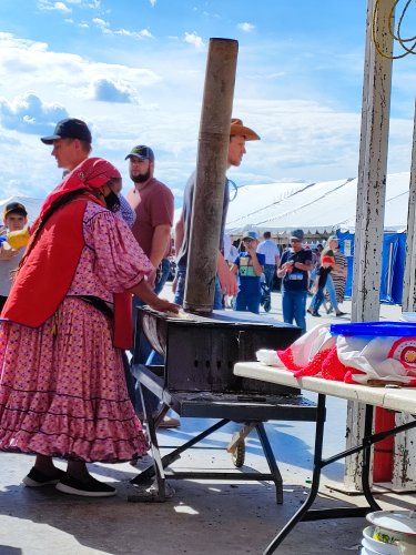 Foto de mujer rarámuri haciendo gorditas en la celebración de los 100 años de los menonitas en Cuauhtémoc